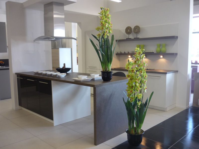 Kücheninsel mit gelbgrünen Orchideen und weißem Geschirr