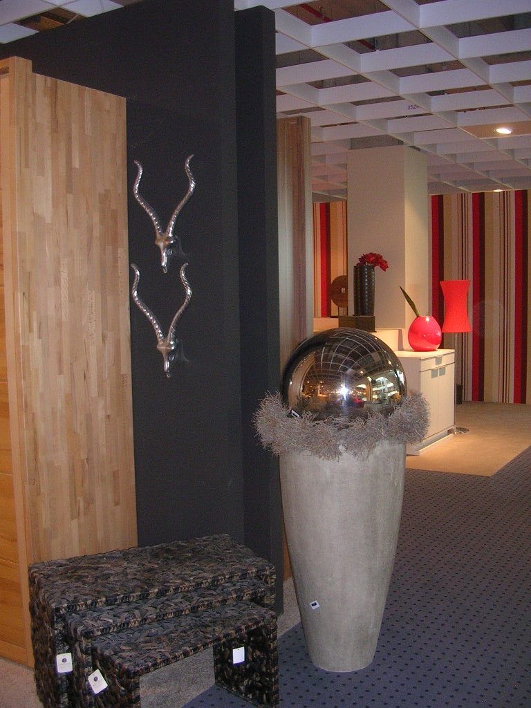 Spiegelkugel in hoher Vase, Wandschmuck und geflochtene Beistelltische im Möbelhaus